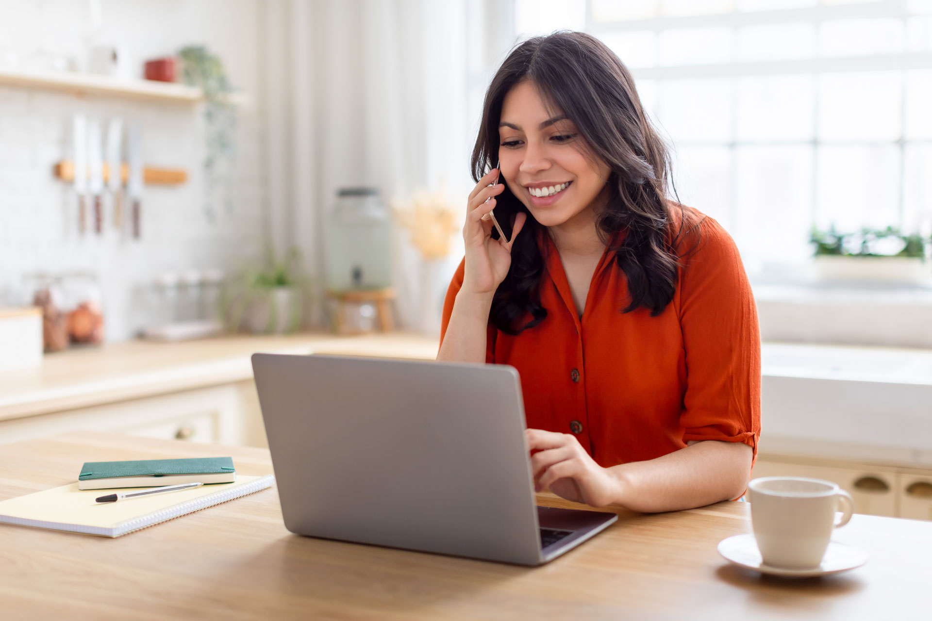 Focused woman on phone with laptop at home